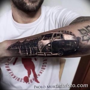 Фото тату Volkswagen Bus (бусика) в реалистичном стиле на предплечье. Рисунок выполнен в черно-серых тонах с детальной проработкой.