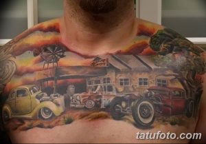 Фотография масштабной татуировки на груди и плече, изображающей автомастерскую с ретро-автомобилями. Детализированный рисунок татуировки.