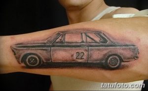 Фото тату Ford Cortina на предплечье, выполненное в реалистичном стиле с использованием черно-белой гаммы и номером 22.