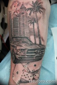 Фото тату Ford Mustang на фоне городского пейзажа и пальм, выполненное в черно-белой гамме с использованием реалистичного стиля.
