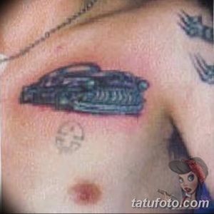 Фотография простой черно-белой татуировки автомобиля на мужской груди. Минималистичный стиль, небольшие размеры, четкие линии.