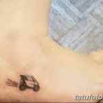 Фотография небольшой татуировки автомобиля на женской стопе. Черно-белый рисунок, минималистичный стиль, аккуратные линии.