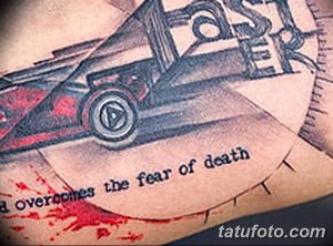 Фото тату на руке с изображением автомобиля и надписью 'a overcomes the fear of death'. Чёрно-серый рисунок в мрачном стиле.