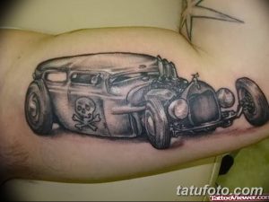 Фото тату на руке с изображением Rat Rod автомобиля с черепами. Черно-белый рисунок татуировки в стиле old school.