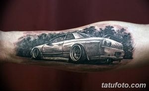 Фото тату на руке: спортивный автомобиль в черно-серых тонах с детальной проработкой. Реалистичный рисунок татуировки с акцентом на динамику.