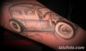 Фото тату на руке: старинный автомобиль в черно-серых тонах. Простой рисунок татуировки с акцентом на контуры и форму.