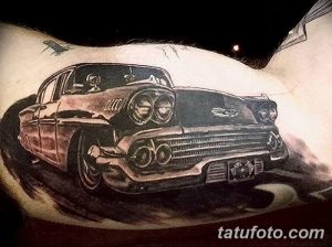 Фото тату: красочный рисунок ретро автомобиля на лопатке, выполненный в реалистичном стиле с использованием ярких цветов и детализированной прорисовки.
