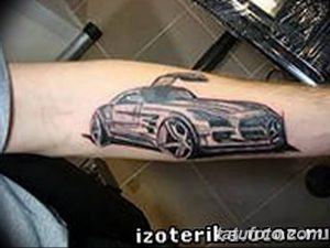 Фото тату: реалистичный рисунок серого Mercedes-Benz с спойлером на предплечье, выполненный с высокой детализацией и использованием теней.