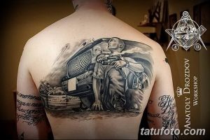 Фото масштабной татуировки на спине с изображением солдата, автомобиля и разрушенного окружения. Реалистичный и детализированный рисунок.