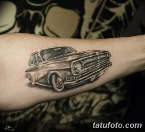 Фотография черно-белой татуировки классического автомобиля на руке. Детализированный рисунок в стиле реализма.