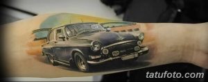 Фотография татуировки старинного автомобиля на руке. Рисунок выполнен в реалистичном стиле с использованием мягких цветов и эффекта винтажности.