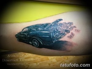 Фотография татуировки автомобиля с открытым багажником, из которого вылетают деньги. Рисунок выполнен в реалистичном стиле.