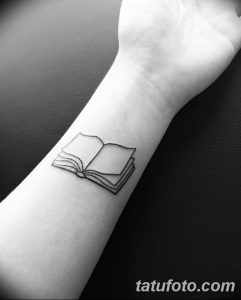 Фото тату: минималистичная открытая книга на запястье, выполненная тонкими черными линиями.