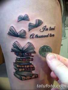 Фото тату: стопка книг и летящие страницы с надписью 'I've lived a thousand lives', выполненное в акварельной технике.