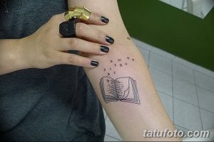 Фото татуировки на предплечье с изображением открытой книги, из которой вылетают буквы. Стиль - графика, тонкие линии.