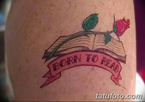 Фотография татуировки на руке с изображением открытой книги и розы. Рисунок выполнен в ярких цветах с использованием контуров.