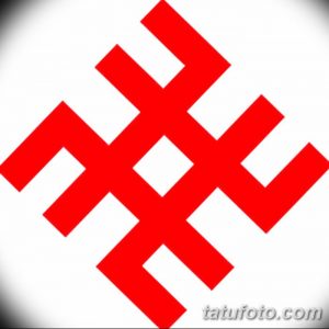 Фото тату в виде красного коловрата, выполненного на белом фоне. Символ представляет собой вращающееся солнце, символизирующее энергию и жизненную силу.