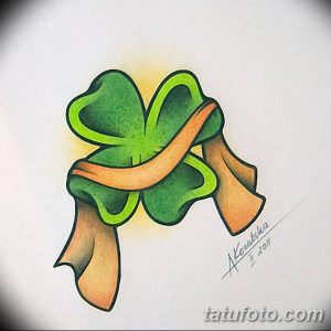 Фото эскиза татуировки с изображением зеленого четырехлистного клевера, перевязанного оранжевой лентой. Яркий и позитивный дизайн для любителей удачи.