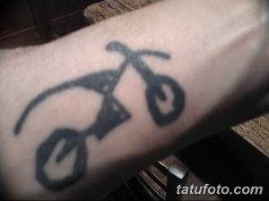 Фото минималистичного тату мотоцикла на руке. Простой силуэт мотоцикла, выполненный в черном цвете.