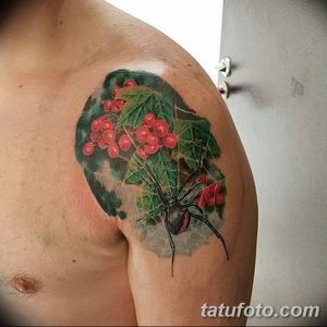 Фото тату рябины на плече мужчины. Красные ягоды и зеленые листья создают яркий и реалистичный рисунок татуировки.