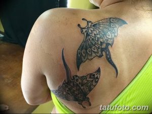 Фото двух татуировок скатов в стиле полинезийской графики на спине женщины, выполненных в черном цвете с детальными узорами.