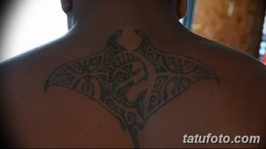 Фото тату: полинезийская татуировка ската на задней части шеи. Черные узоры, геометрические формы, традиционный стиль.