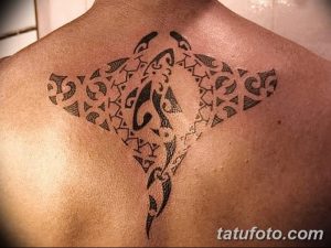 Фото тату ската в стиле трайбл на спине. Черный рисунок с сложными геометрическими узорами и спиралями, создающими образ ската.