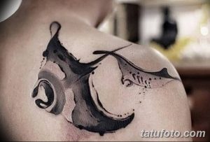 Фото тату: минималистичная татуировка ската на плече, выполненная в технике brushwork с использованием черных чернил и эффекта размытия.