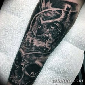 Фото тату на руке, выполненное в технике blackwork. Изображение совы, переходящей в череп, с использованием только черного цвета.