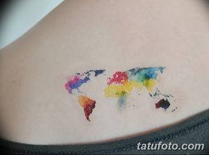 Фото тату: красочная карта мира, выполненная в технике акварели на спине. Изображение выглядит как размытое пятно, с переходом от одного цвета к другому.