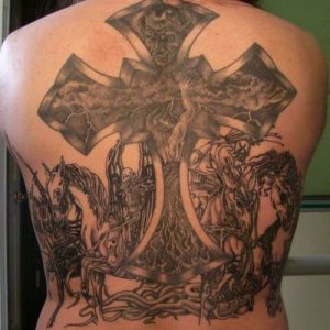 Фото тату апокалиптического креста на спине мужчины. Черно-серый рисунок татуировки с изображением демонов, всадников и молний.