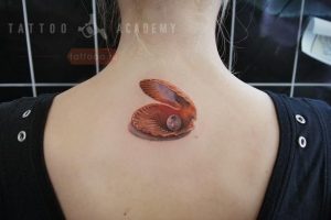 Фото нежной татуировки раковины с жемчужиной на спине. Пастельные тона, плавные линии, женственный рисунок татуировки.