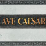 Фото татуировки с надписью 'Ave Caesar' в декоративной рамке. Использованы золотистые и серые оттенки, создающие эффект старины. Расположение - предположительно, на спине.