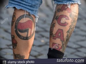 Фотография татуировок на ногах: анархистский символ и надпись 'ACAB'. Разноцветные татуировки, выполненные в различных стилях.