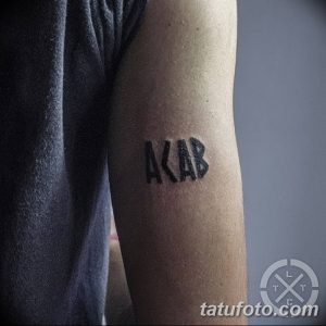 Фотография минималистичной татуировки 'ACAB', выполненной черными чернилами на предплечье. Простые буквы, четкие линии, небольшой размер.