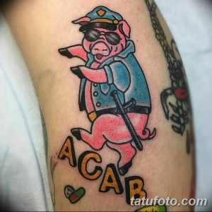 Фото тату с изображением свиньи в полицейской форме и надписью ACAB. Цветной рисунок татуировки, выполненный в стиле традиционной татуировки. Пример тату для тех, кто хочет выразить свою позицию.