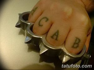 Фото тату надписи 'ACAB' на костяшках пальцев. Маленькие черные татуировки, выражающие протест и смелость.