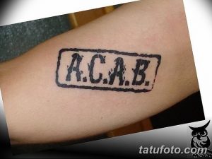 Фото тату надписи 'ACAB' в черной прямоугольной рамке. Простой и лаконичный дизайн, выражающий протестную позицию.
