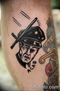 Фото тату с изображением полицейского с дубинкой и надписью 'ACAB'. Черно-белая татуировка, выражающая протест и критику.