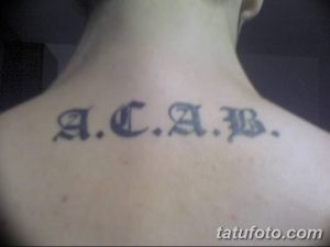Фото тату надписи 'ACAB' на затылке. Черные чернила, простой шрифт, минималистичный дизайн. Подходит для тех, кто хочет выразить свою позицию.