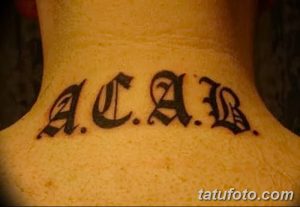 Фото тату: надпись 'ACAB' на шее, выполненная черными готическими буквами с небольшими засечками.