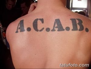 Фото тату: надпись 'A.C.A.B.' на спине, выполненная простыми черными буквами без каких-либо дополнительных элементов.