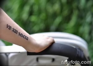 Фото тату: минималистичная татуировка с римскими цифрами 'VII.XIII.MMXXII' на внутренней стороне предплечья. Черный рисунок, тонкие линии.