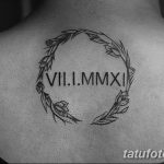 Фото тату на спине: римские цифры VII.I.MMXI заключены в венок из листьев и цветов. Черно-белая татуировка, минималистичный стиль.