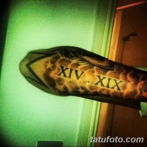 Фото тату на руке: римские цифры XIV и XIX, заключенные в языки пламени. Черно-оранжевая цветовая гамма, динамичная композиция.