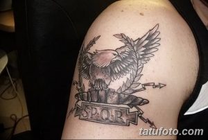 Фото тату римского орла с лавровыми ветвями и надписью SPQR на плече. Черно-серая графика, детализированная проработка.