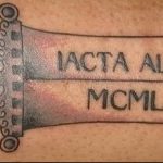Фото тату с изображением меча и римскими цифрами IACTA ALEA EST MCMXLVI на спине. Цветной рисунок татуировки, исторический стиль, детализированный эскиз.