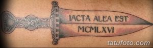 Фото тату с изображением меча и римскими цифрами IACTA ALEA EST MCMXLVI на спине. Цветной рисунок татуировки, исторический стиль, детализированный эскиз.