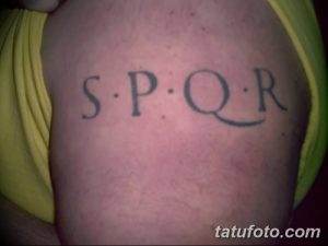 Фото тату с надписью SPQR на плече. Черно-серый рисунок татуировки, исторический стиль, латинская фраза.