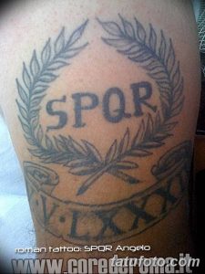 Фото тату на руке: римский венок с надписью SPQR и римскими цифрами, выполненный в традиционном стиле.